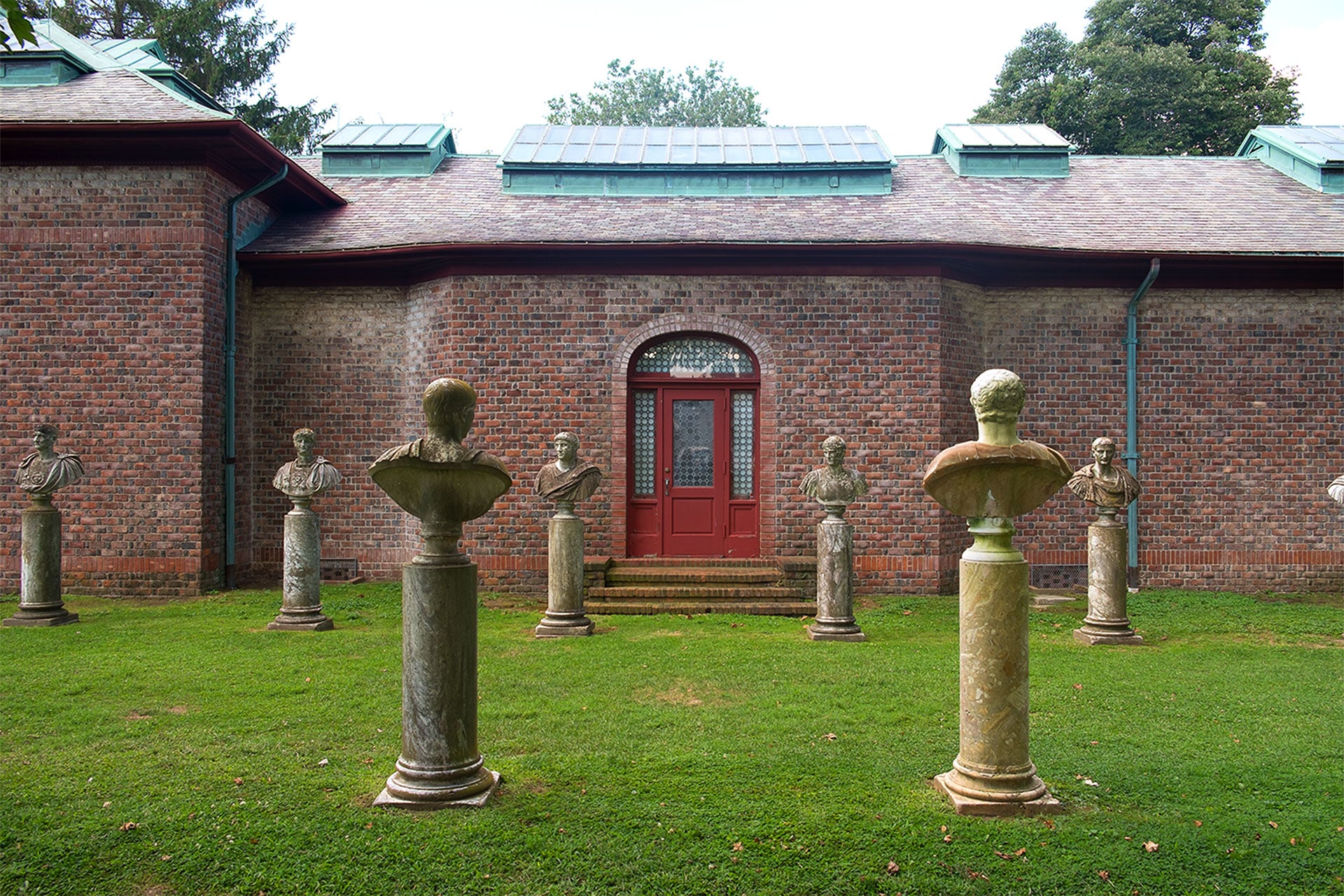 frontal view of brick building, statues on grassy lawn