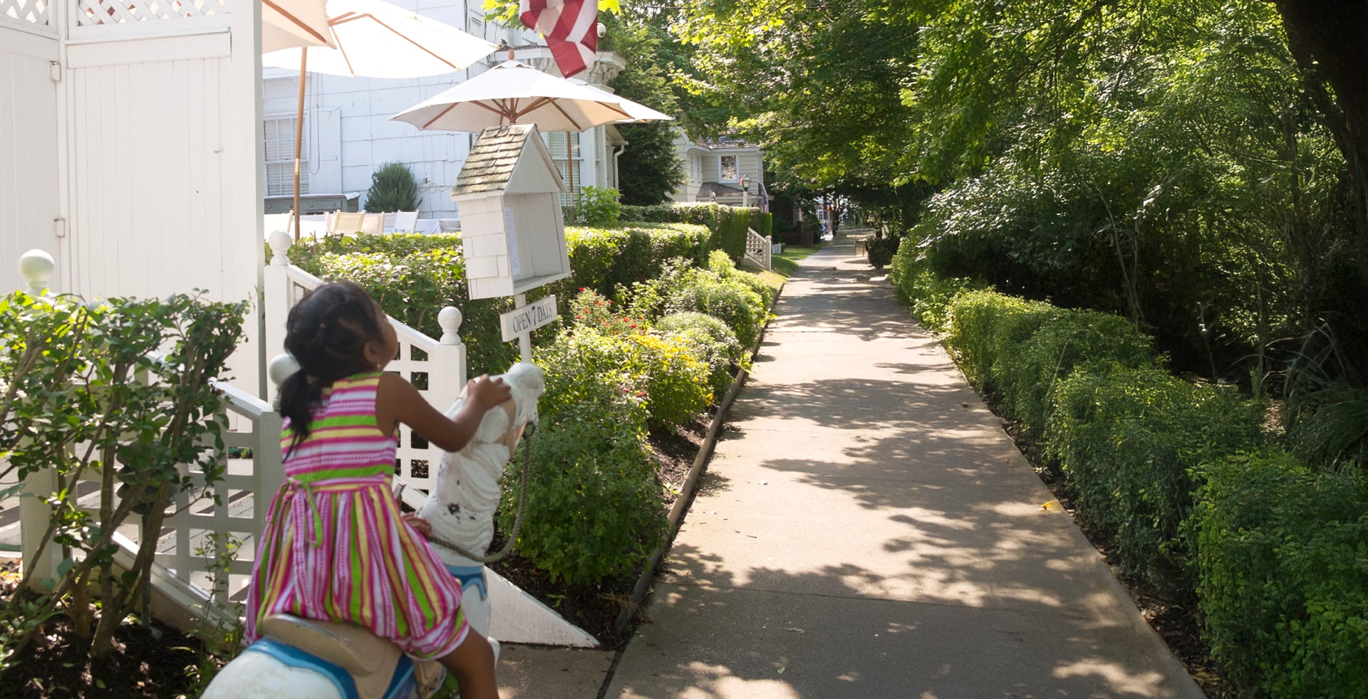 girl sitting on toy horse on sidewalk